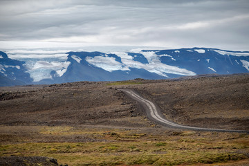 Typical Icelandic highland landscape with empty gravel road.