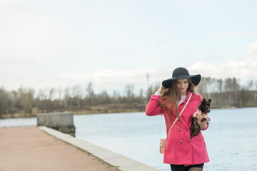 girl in a pink coat and a black hat with a small dog