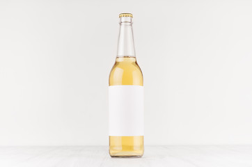 Transparent longneck beer bottle 500ml with blank white label on white wooden board, mock up....