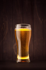 Weizen beer glass with golden sparkling lager on dark wood board. Template for advertising, design, branding identity, restaurant menu, cover.