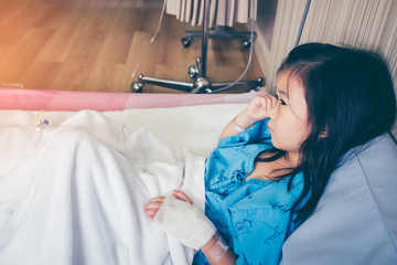 Fototapeta premium Illness asian child admitted in hospital with saline intravenous on hand.