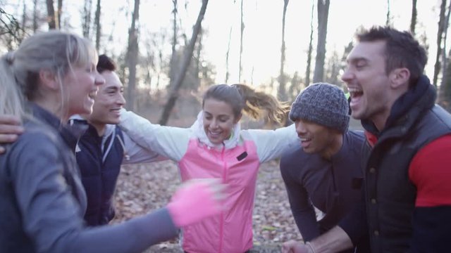 Happy friends on a run in the woods stop for a break and feel the buzz of adrenaline.