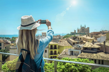 Woman tourist with her phone camera in hands shooting in Palma d