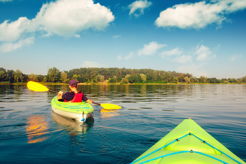 Boy in life jacket on green kayak