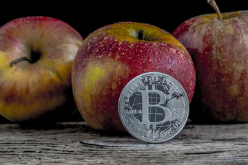 Bitcoin and apples on old wood board isolated on black background