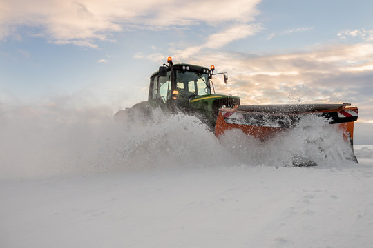 Traktor mit Schneepflug bei der Schneeräumung in Österreich. Landwirtschaftlich ausgerichtete Betriebe nutzen den Winter um Ihre Maschinen besser auslasten zu können.