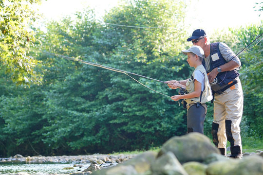 Father teaching son how to fly-fish in river