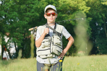 Young boy standing in field with fishing equiment