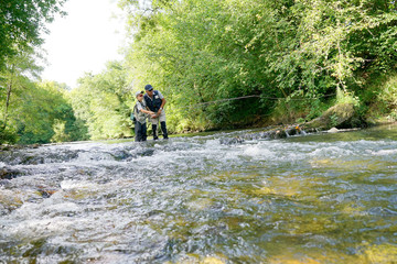 Obraz premium Father and son fly-fishing in river