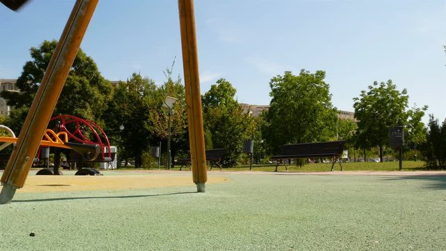 empty swing with chains swaying at playground for child, moved, on green meadow background, 4k video