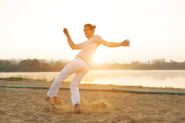 Fototapeta na wymiar Athletic capoeira performer making movements on the beach