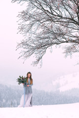 Beautiful winter portrait of young woman in the winter snowy scenery.