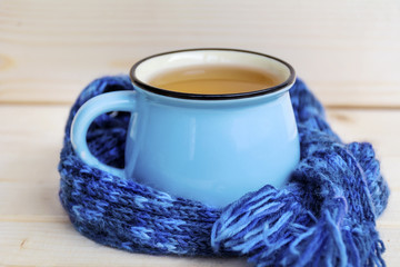 Obraz na płótnie Canvas blue mug of tea wrapped with woolen scarf 