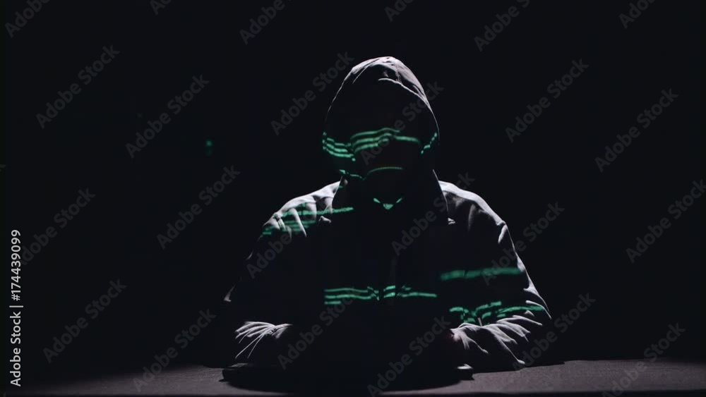 Poster spy is typing virus patches on the keyboard for hacking. black background. silhouette