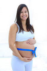 Happy pregnant woman measuring her tummy and waist.