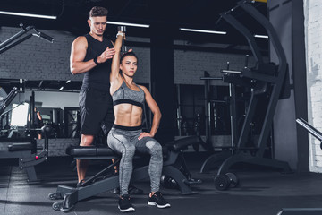 trainer helping woman to exercise with dumbbell