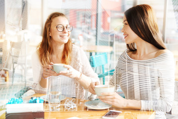 Cheerful girls drinking coffee together