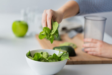 close up of woman hand adding spinach to bowl