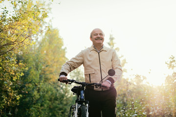 Senior man go for a walk with bike in countryside
