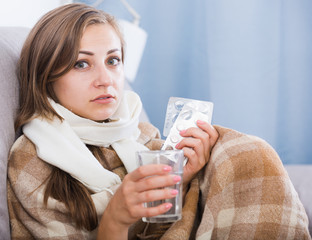 Ill girl on couch with drink and medicine