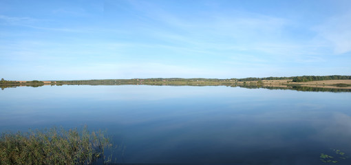 Fototapeta premium Panoramic view of countryside landscape with hills, lake, hills and forest far away in sunny summer day