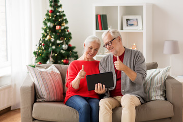 Obraz premium happy senior couple with tablet pc at christmas