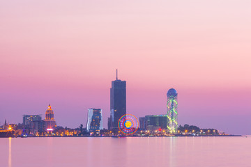 View from Sea Beach to Illuminated cityscape with Skyscrapers And Tower at sunset, Batumi, Adjara, Georgia