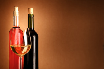 Glass of white wine in front of bottles with copyspace