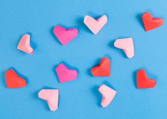 Obraz premium Red, Bright and Pale Pink Paper Origami Hearts on Blue Background