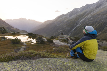 Young alpinist enjoys the warming sunbeams after a strict mountain tour