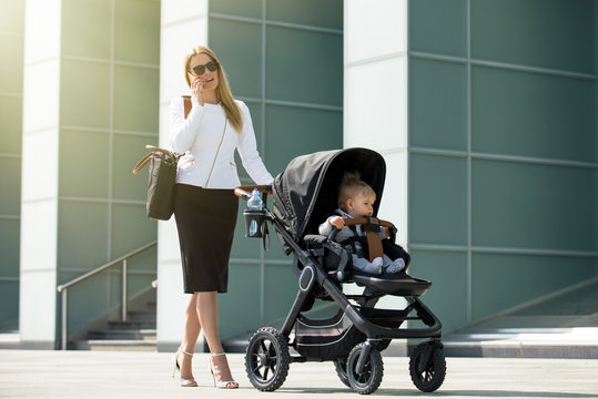 Business woman talking on the phone and pushing baby stroller