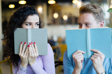 Young students spending time in coffee shop reading books