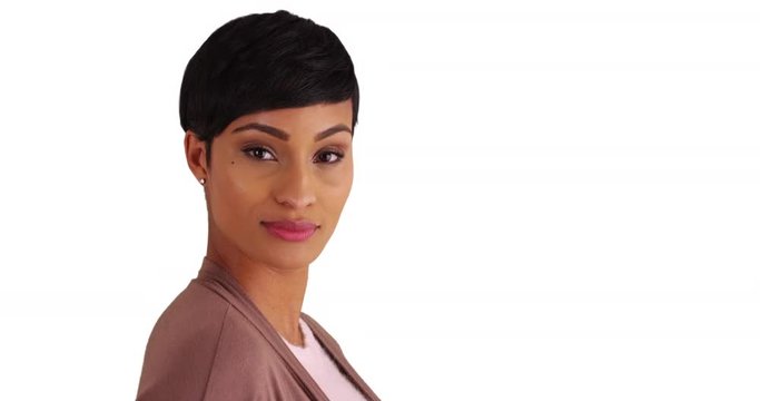 Close up of lovely black female with pixie haircut smiling at camera on white background with copyspace. Close-up of African American woman in her 20s looking at camera with confident expression 
