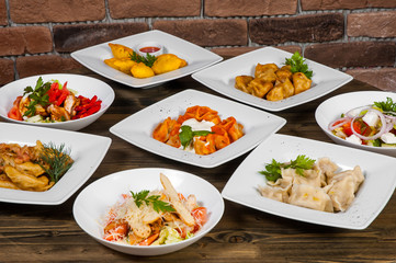 Set of different salads, dumplings and ravioli on a wooden table