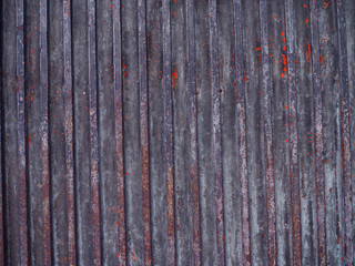 Old rusty red peeled stained vertical groove line pattern iron gate wall background