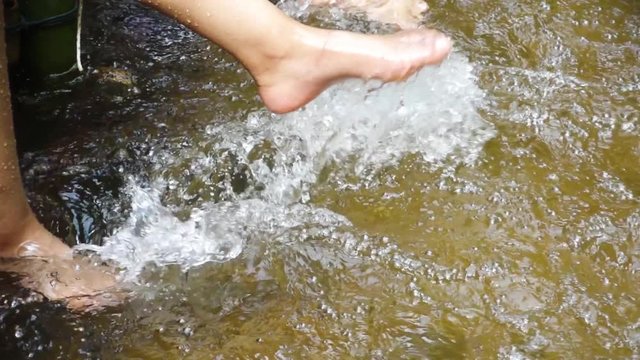 Slow motion of young woman dangling feet in the water.
