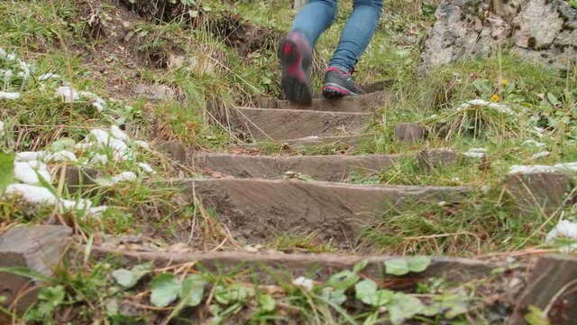 Handheld 4k shot of female legs in trekking boots walking along Adolf Munk Trail in the Dolomites on a late autumn or early winter cloudy day. Healthy lifestyle, travel concept, hiking experience.