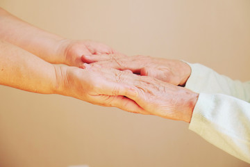 Close up of senior woman and young woman holding hands. Care and support concept 