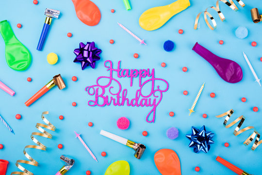 Happy birthday background. Festive candles, party confetti, balloons, streamers and decoration on blue background. Colorful celebration background. Flat lay