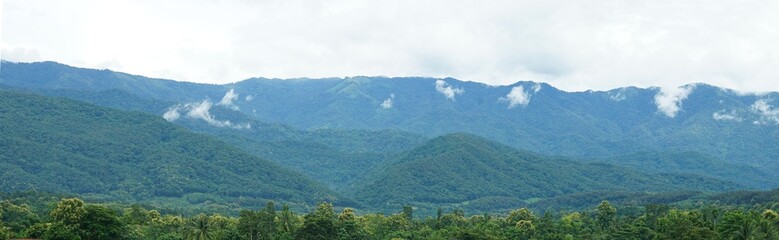 Fototapeta na wymiar Panorama of green mountain range with soft white clouds