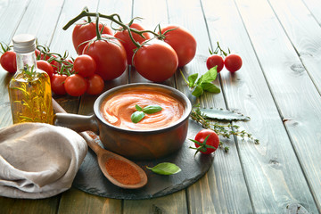 Tomato cream soup in ceramic bowl served with cream and basil, space
