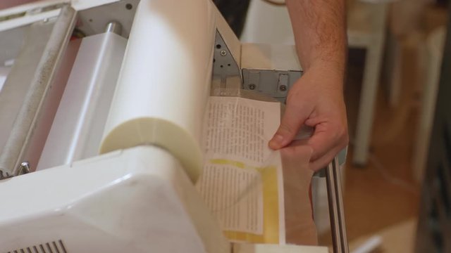 Сaucasian male working with roll laminator