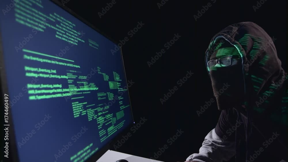 Poster spy hacking computer sitting in a dark room. black background