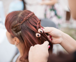 Naklejka premium the stylist weaves the female braids on the head