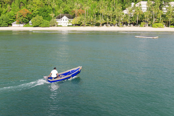 Obraz premium Back of skipper controlling small boat to coast.