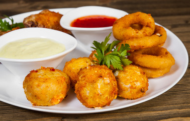 set of appetizers. salted balls, chicken wings, onion rings, sauce on a wooden background. 