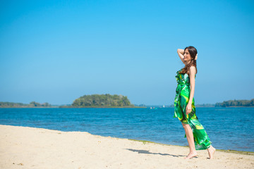 Obraz na płótnie Canvas Middle aged stylish woman wear in long silk dress on a beach rest at good sunny day