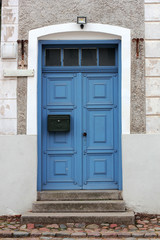 Closed blue door with the mailbox in a stone house