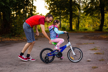Fototapeta premium Father teaching his daughter to ride a bike