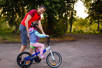 Father teaching his daughter to ride a bike